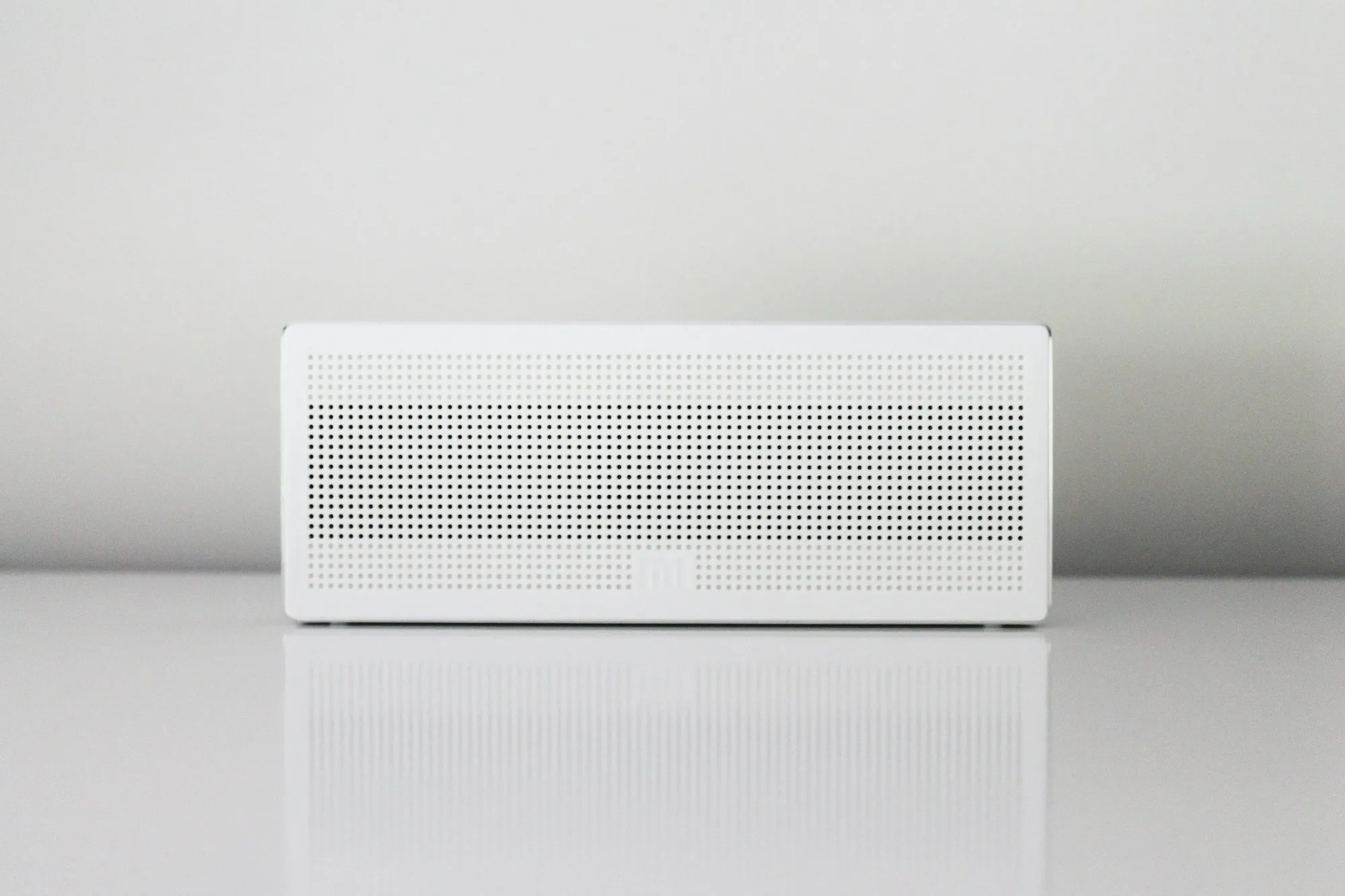 A compact white unit with a perforated grille on a white table